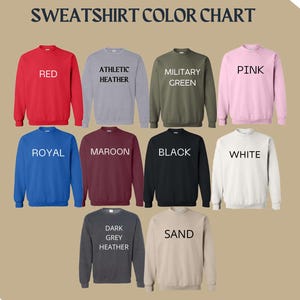 May include: Color chart showing 10 different sweatshirt colors. The colors are: red, athletic heather, military green, pink, royal, maroon, black, white, dark grey heather, and sand.