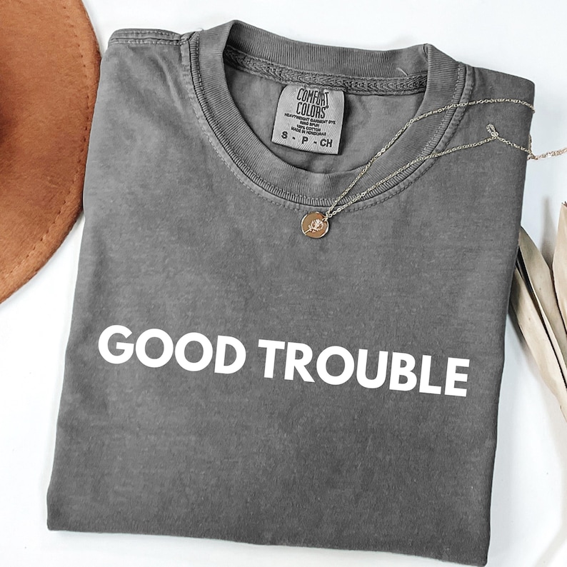 May include: Gray t-shirt with the text "GOOD TROUBLE" printed in white on the front.