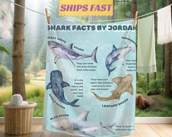 May include: A light blue beach towel featuring illustrations of various shark species, including Great White, Hammerhead, Whale, Leopard, and Blue Sharks. The towel includes facts about each shark, with the text "SHARK FACTS BY JORDAN" at the top.
