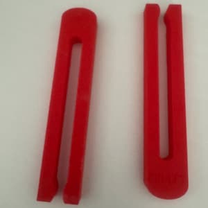 May include: Two bright red, U-shaped foam hair styling tools. One is a rounded rectangle with a central slot, and the other is a longer, thinner version with a similar slot. Both are on a white background.