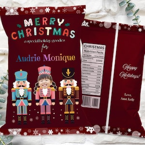 Könnte beinhalten: Eine weinrote Weihnachtstüte mit dem Text "Merry Christmas" und "Audrie Monique" in bunten Buchstaben. Die Tüte zeigt drei Nussknacker-Illustrationen und eine "Happy Holidays"-Nachricht.
