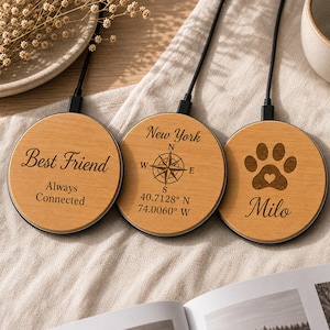 Può includere: Tre caricabatterie wireless circolari in legno con cavi di alimentazione neri. Il primo presenta il testo "Best Friend Always Connected". Il secondo mostra un design a bussola con "New York" e coordinate. Il terzo mostra un'impronta di zampa e "Milo".
