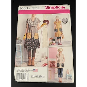 Könnte beinhalten: Simplicity Schnittmuster 1080 A mit mehreren Kleiderdesigns. Das Muster enthält Bilder der fertigen Kleidungsstücke mit Details wie Taschen und verschiedenen Stoffkombinationen. Die Verpackung trägt den Text "dottie angel" und "Designed and printed in the USA".