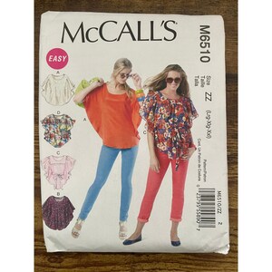 Puede incluir: Sobre de patrón de costura McCall's M6510 con ilustraciones de cuatro estilos de blusas. El frente muestra a dos personas con una blusa naranja estilo poncho y una blusa floral con lazo en la cintura, talla ZZ.