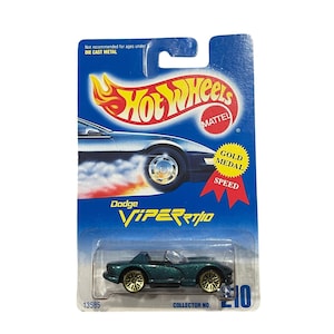 Puede incluir: Un coche de juguete Dodge Viper RT/10 Hot Wheels de metal fundido a presión en un paquete azul y blanco. El coche es verde azulado con ruedas doradas. El paquete tiene el logotipo de Hot Wheels y el texto "Gold Medal Speed". Número de coleccionista 210.