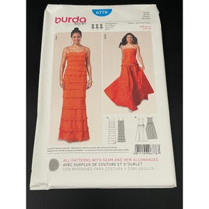 May include: A Burda Style sewing pattern packet featuring two orange dresses. The packet includes illustrations of the dresses, diagrams, and the text "ALL PATTERNS WITH SEAM AND HEM ALLOWANCES".