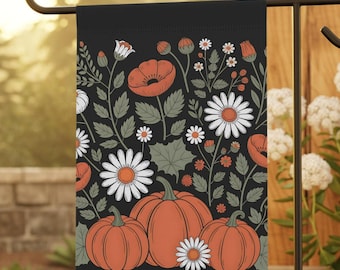 May include: A black garden flag featuring a fall-themed design. The flag showcases orange pumpkins, white daisies, and red poppies against a backdrop of green leaves and stems. The flag is displayed on a black metal stand.