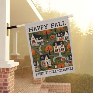 May include: A rectangular garden flag featuring the text HAPPY FALL at the top and RESIST BILLIONAIRES at the bottom. The center displays a pattern of white houses, orange pumpkins, black cats, and autumn trees on a dark green background.