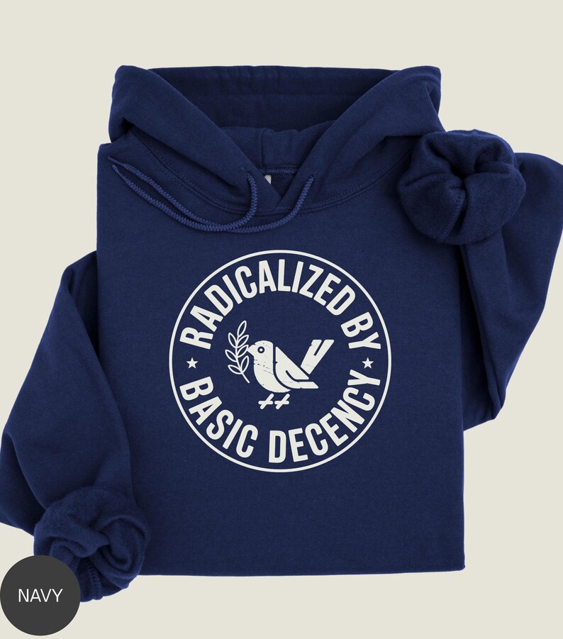 May include: Navy blue hoodie with a white graphic. The graphic is a circle with the words "RADICALIZED BY BASIC DECENCY" surrounding a bird holding a sprig. The hoodie has a drawstring hood and a front pocket.