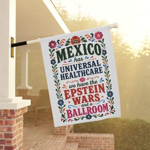 Może przedstawiać: Biała flaga z napisem "MEXICO has UNIVERSAL HEALTHCARE we have the EPSTEIN WARS and a BALLROOM" w różnych kolorach i czcionkach. Flaga jest ozdobiona kwiatowymi wzorami i wisi na zewnątrz.
