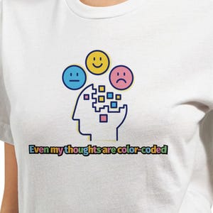 May include: White t-shirt featuring a graphic of a head with different coloured thought bubbles. The text "Even my thoughts are color-coded" is printed below the graphic.