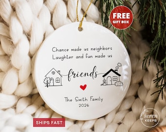 May include: A round white ceramic ornament featuring black line art of two houses with the text "Chance made us neighbors Laughter and fun made us friends" and a small red heart. The bottom includes "The Smith Family" and "2026".