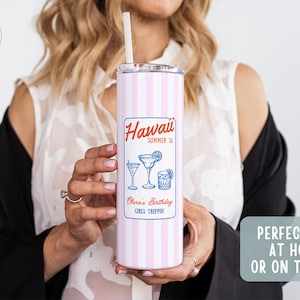 May include: A pink and white striped tumbler with a straw, featuring a label that reads "Hawaii Summer '26" with cocktail illustrations. The tumbler is designed for home or on-the-go use.