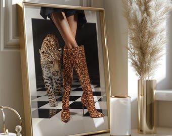 Könnte beinhalten: Gerahmtes Kunstwerk mit einem Leoparden und Overknee-Stiefeln mit Leopardenmuster. Das Kunstwerk befindet sich in einem goldenen Rahmen und wird auf einer weißen Oberfläche präsentiert. Eine goldene Vase mit Pampasgras und ein weißer Kerzenhalter sind ebenfalls vorhanden.