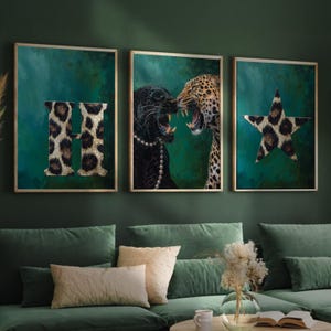 Puede incluir: Tres impresiones artísticas enmarcadas con un fondo verde. Una impresión presenta la letra "H" con estampado de leopardo. Otra representa dos grandes felinos, uno negro y otro leopardo, enfrentados. La tercera impresión muestra una estrella con estampado de leopardo.