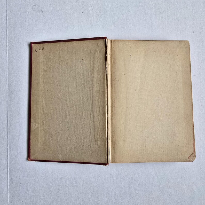 Peut inclure: Un livre ouvert avec des pages vieillies de couleur cr&egrave;me. La couverture est rouge fonc&eacute; et le dos est visible. La page de gauche porte l'inscription manuscrite "814 E" dans le coin sup&eacute;rieur gauche. Le livre est ouvert sur une surface blanche.