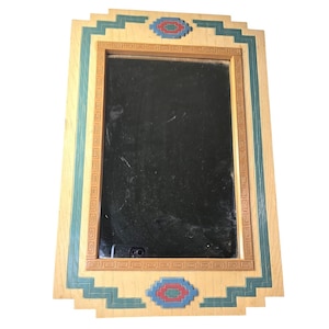 May include: Rectangular wooden mirror with a decorative frame. The frame features a light wood color with teal and brown accents. The design includes geometric patterns and a central mirror.