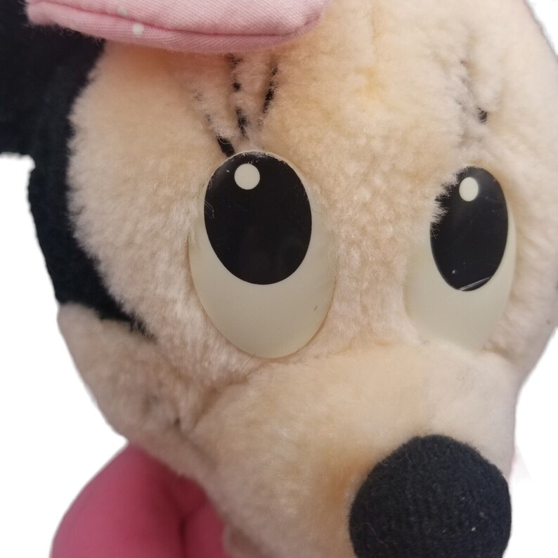 Puede incluir: Un juguete de peluche de un rat&oacute;n de dibujos animados con ojos grandes, un lazo rosa y una nariz negra. El juguete est&aacute; hecho de piel suave y blanca.