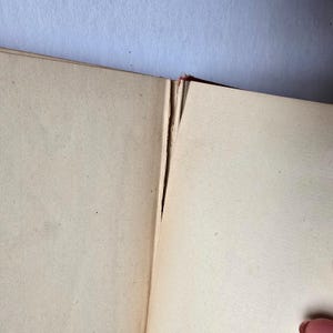 Peut inclure: Livre ouvert avec des pages jaunies et blanch&acirc;tres. La reliure est visible, montrant le dos et la connexion des pages. Les pages sont l&eacute;g&egrave;rement jaunies, sugg&eacute;rant l'&acirc;ge. Le fond est bleu clair.