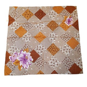 May include: A brown and white patterned fabric with a diamond pattern and purple flowers. The fabric has a vintage feel.