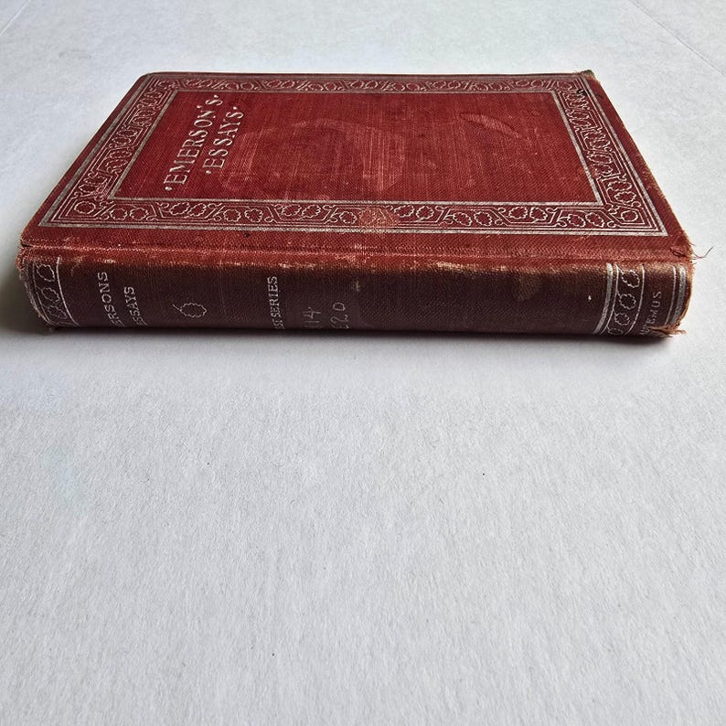 Peut inclure: Un livre ancien intitul&eacute; "Emerson's Essays" avec une couverture rouge et une bordure argent&eacute;e d&eacute;corative. La tranche du livre affiche le titre et les informations de la s&eacute;rie. Le livre est en bon &eacute;tat, montrant des signes d'&acirc;ge.