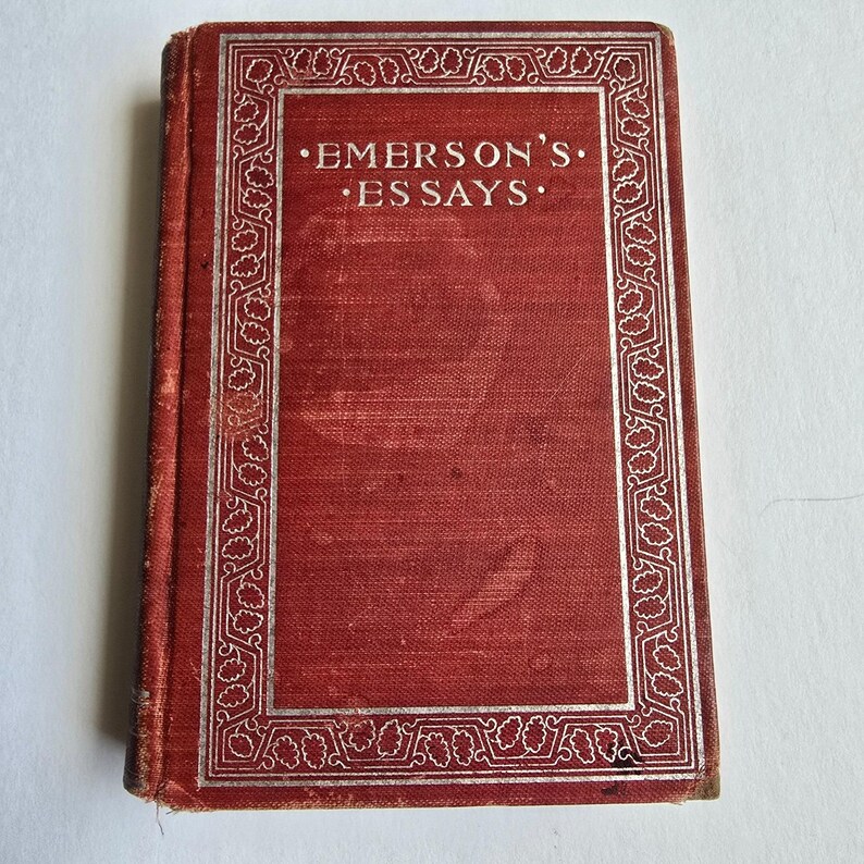 Peut inclure: Un livre ancien avec une couverture rouge et le titre "EMERSON'S ESSAYS" en lettres argent&eacute;es. La couverture a une bordure argent&eacute;e d&eacute;corative. Le livre semble usag&eacute;, sugg&eacute;rant qu'il s'agit d'une antiquit&eacute; ou d'un article d'occasion.