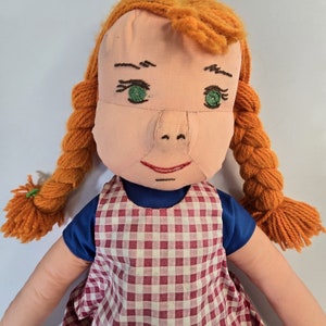 May include: A handmade doll with red yarn hair, green eyes, and a red and white checkered dress.