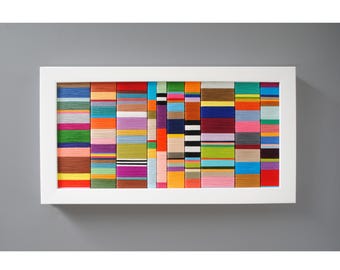 May include: A framed artwork featuring a colourful abstract design made of thin strips of fabric in various colours and patterns.
