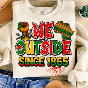 May include: Cream-colored sweatshirt with the text "WE OUTSIDE SINCE 1865" in red, green, and yellow. Features a fist in the colors of the Pan-African flag, a map of Africa, and roots.
