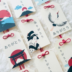 以下が含まれることがあります： 富士山、鶴、芸者のイラストが描かれた、日本のスタイルのギフトタグのコレクション。各タグには日本語の「ありがとう」という言葉が書かれており、赤い紐で結ばれています。