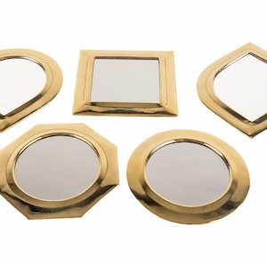 Puede incluir: Conjunto de cinco espejos decorativos de color dorado con diferentes formas, incluyendo una lágrima, un cuadrado, un octógono y dos espejos redondos.