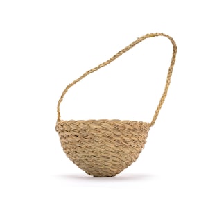Może przedstawiać: Tkany kosz z zaokrągloną podstawą i plecionym uchwytem. Kosz wykonany jest z włókien w naturalnym kolorze, a uchwyt jest łukowaty u góry. Kosz jest przeznaczony do przenoszenia za uchwyt.