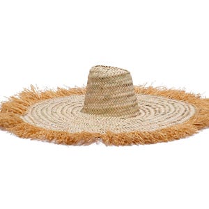 Op de afbeelding: Een strohoed met brede rand, een cilindrische kroon en een gefranjerde rand. De hoed is gemaakt van natuurlijk gekleurd stro met een lichtbruine franje. De hoed heeft een diameter van ongeveer 46 cm.