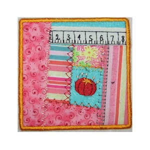 Può includere: Un quadrato di tessuto patchwork colorato con un cuscinetto per aghi ricamato rosso al centro. Il tessuto è cucito insieme in una varietà di motivi e colori, tra cui rosa, blu, verde e giallo. Il quadrato è circondato da un bordo dorato.