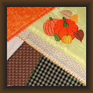 Può includere: Un blocco di patchwork per trapunta con un motivo a scacchi marrone, bianco e nero, un tessuto marrone strutturato e un tessuto verde chiaro con zucche e foglie ricamate.