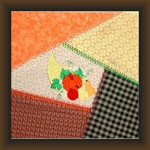 May include: A patchwork quilt with a cornucopia design in the center. The cornucopia is filled with fall harvest items like pumpkins, gourds, and leaves. The quilt is made of different fabrics in shades of orange, brown, yellow, and green.