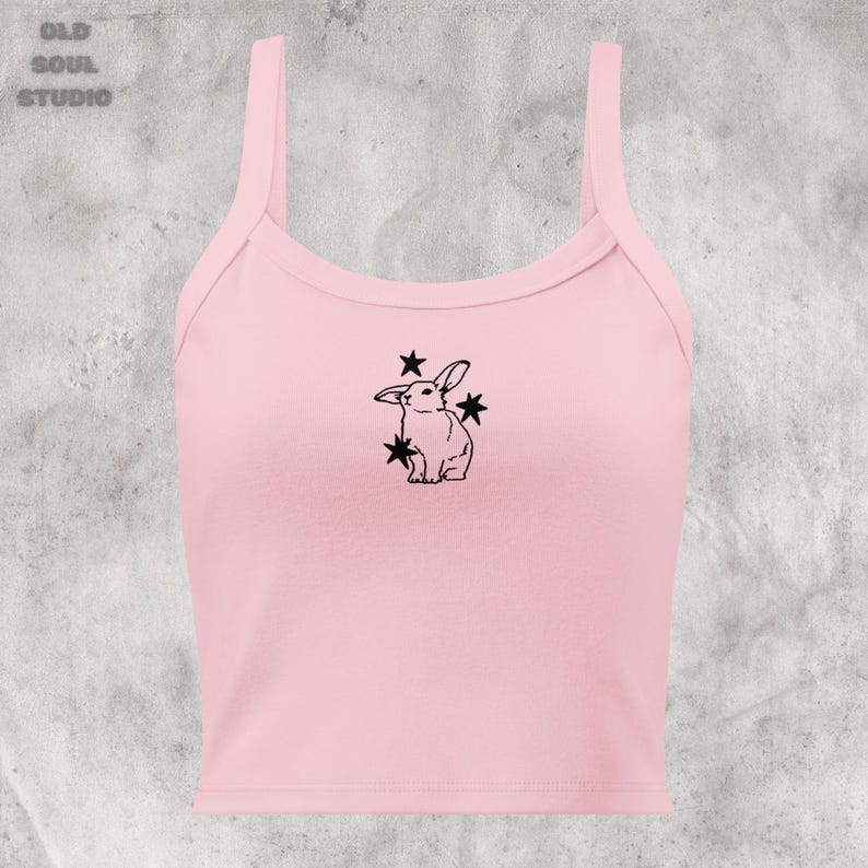 May include: A pink sleeveless crop top with a black outline of a rabbit with stars around it.
