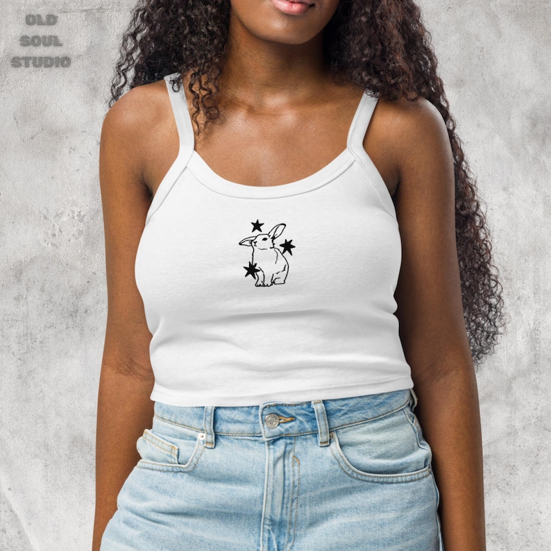 May include: A white crop top tank with a black outline of a rabbit with stars around it.