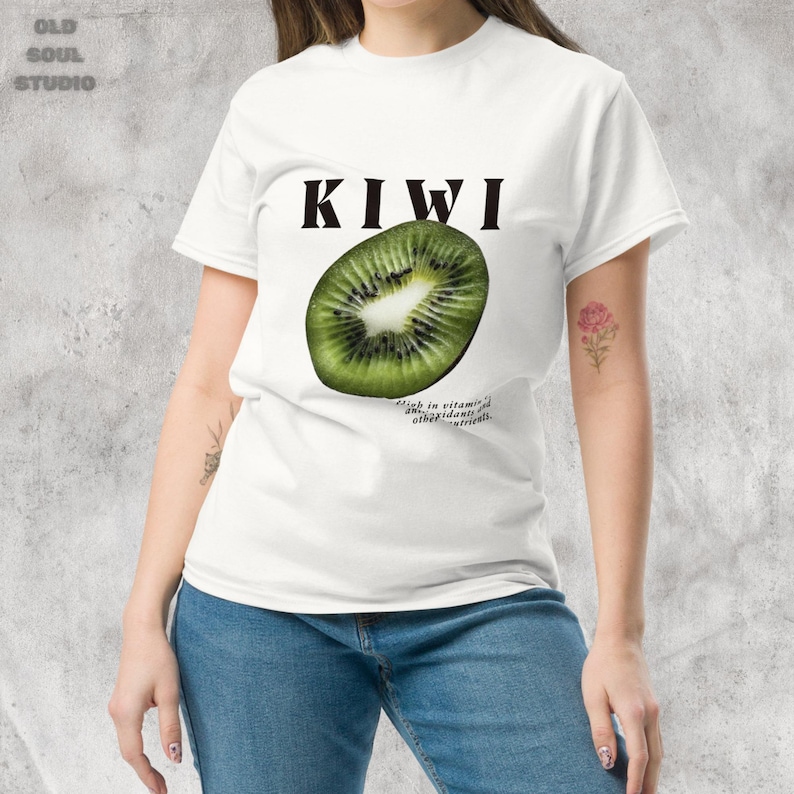 White Y2K aesthetic unisex t-shirt featuring a bold KIWI text, a vibrant kiwi graphic, and small retro-inspired text below. A tropical, playful vibe perfect for casual, streetwear looks