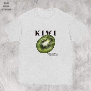 Gray Y2K aesthetic unisex t-shirt featuring a bold KIWI text, a vibrant kiwi graphic, and small retro-inspired text below. A tropical, playful vibe perfect for casual, streetwear looks