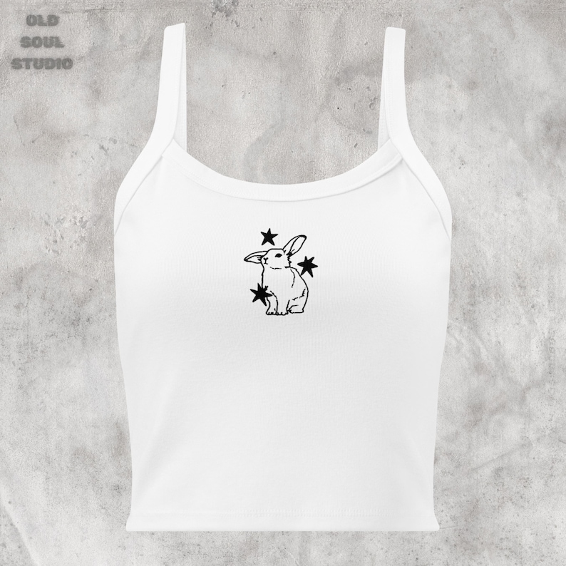 May include: White crop top with a black line drawing of a rabbit surrounded by stars.