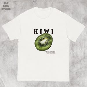 White Y2K aesthetic unisex t-shirt featuring a bold KIWI text, a vibrant kiwi graphic, and small retro-inspired text below. A tropical, playful vibe perfect for casual, streetwear looks