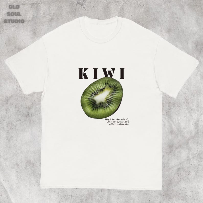 White Y2K aesthetic unisex t-shirt featuring a bold KIWI text, a vibrant kiwi graphic, and small retro-inspired text below. A tropical, playful vibe perfect for casual, streetwear looks