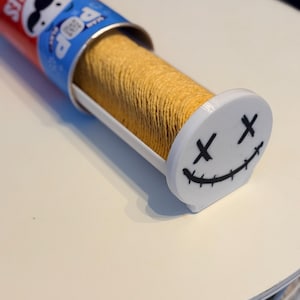 Könnte beinhalten: Eine teilweise geöffnete Pringles-Kartoffelchip-Verpackung mit einem weißen und schwarzen Smiley-Gesicht-Chip-Spender. Der Behälter ist rot mit dem Pringles-Logo und blauen Akzenten. Die Chips sind goldbraun.