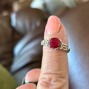 May include: A silver ring with a red gemstone set in a decorative filigree design.