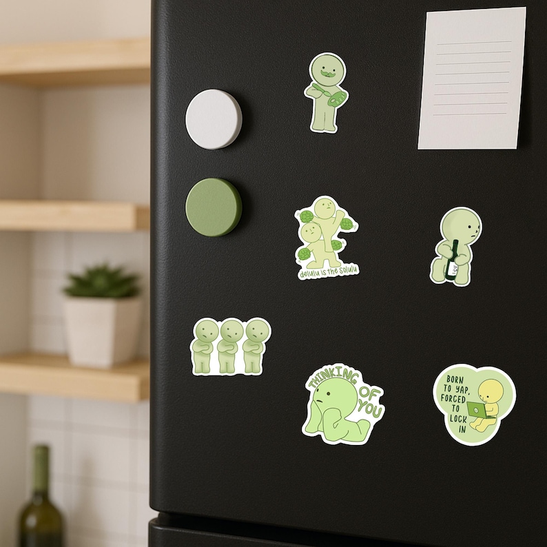 May include: A collection of green stickers with cartoon figures and text on a black refrigerator. The stickers feature various poses and phrases, including "Thinking of You" and "Born to Yap, Forced to Lock In."