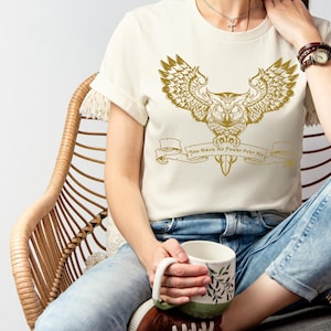 May include: A white t-shirt featuring a gold owl graphic and the text "You Have No Power Over Me".