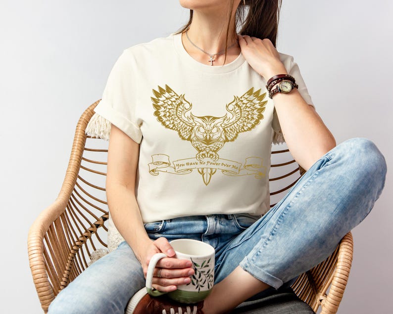 May include: A white t-shirt featuring a gold owl graphic and the text "You Have No Power Over Me".
