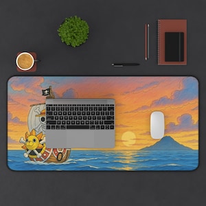 May include: A rectangular desk mat featuring a vibrant illustration of a ship sailing on the ocean under a sunset sky. The ship has a skull and crossbones flag and a cartoon character on the front. A laptop, mouse, and keyboard are on the mat.
