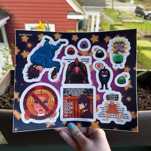 May include: A sheet of colorful stickers featuring various cartoon characters and phrases. Designs include a person falling, a chicken, and a character with a heart. Text includes "Certified Haley Hater" and "BANG! BANG! BANG!".